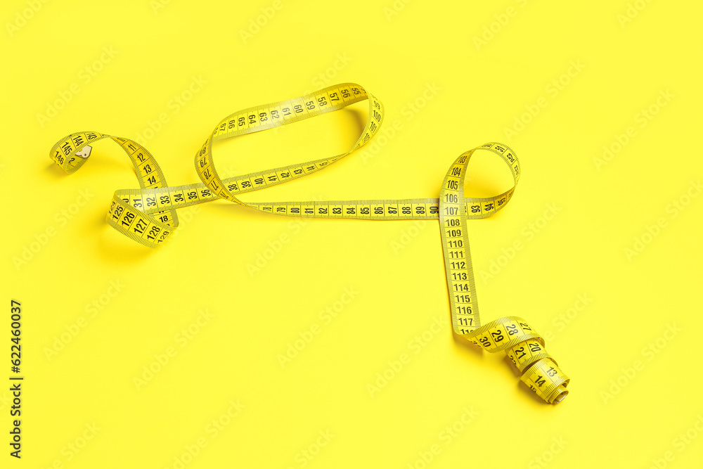 Stylish measuring tape on yellow background