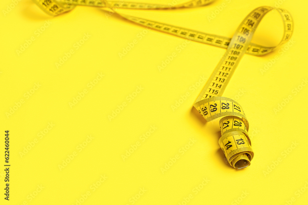 Stylish measuring tape on yellow background, closeup