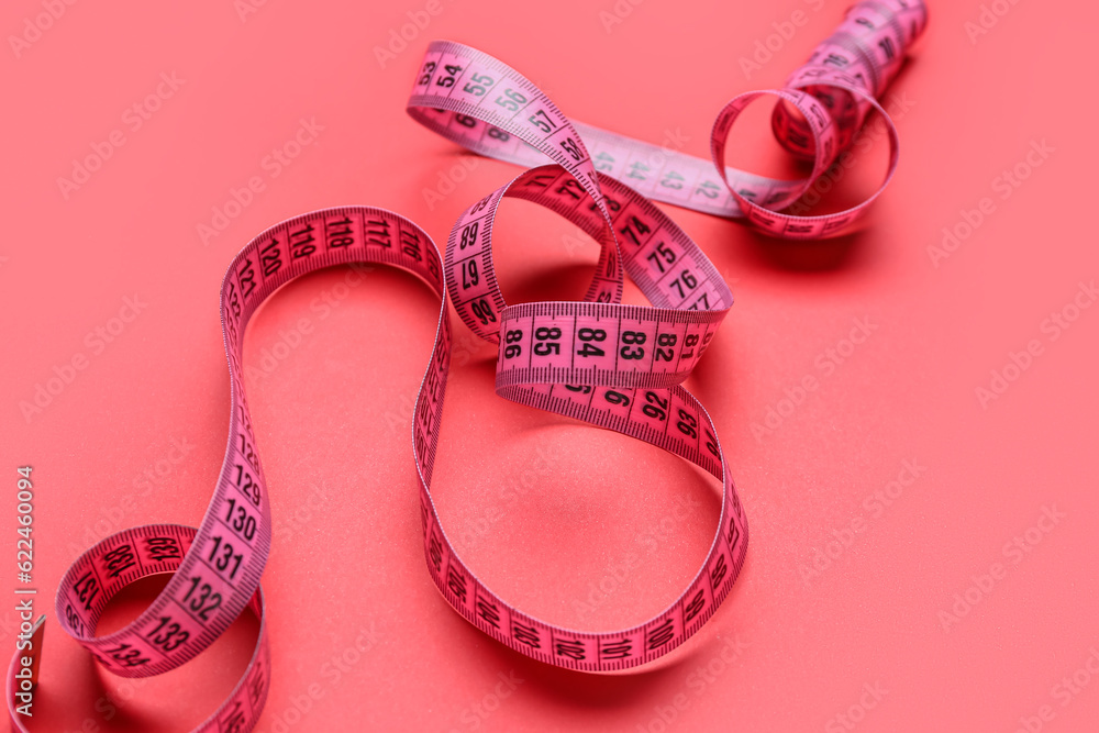 New measuring tape on red background, closeup