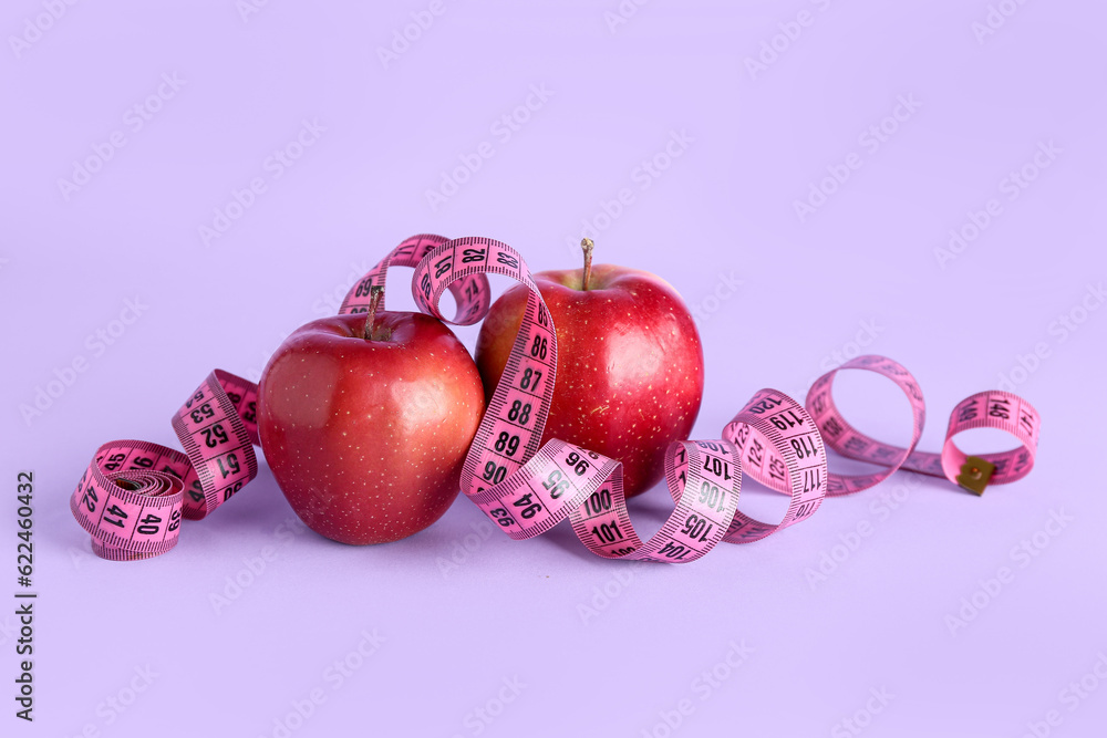 Apples and measuring tape on purple background. Diet concept