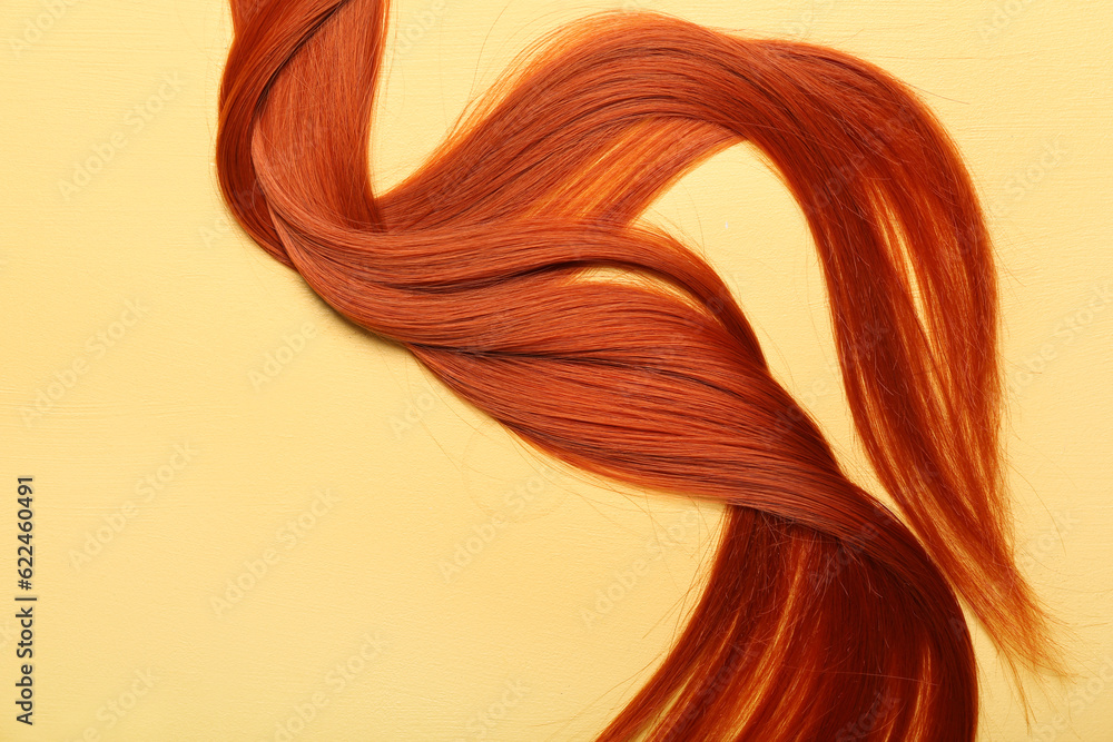 Ginger hair strand on yellow background, closeup