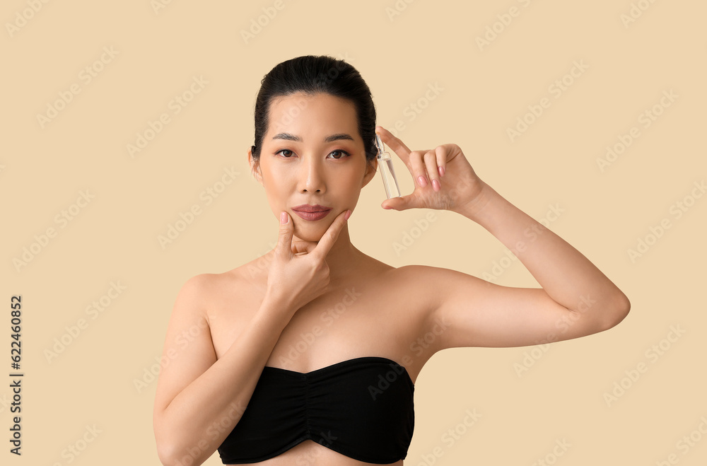 Beautiful Asian woman with ampule on beige background. Skin care concept