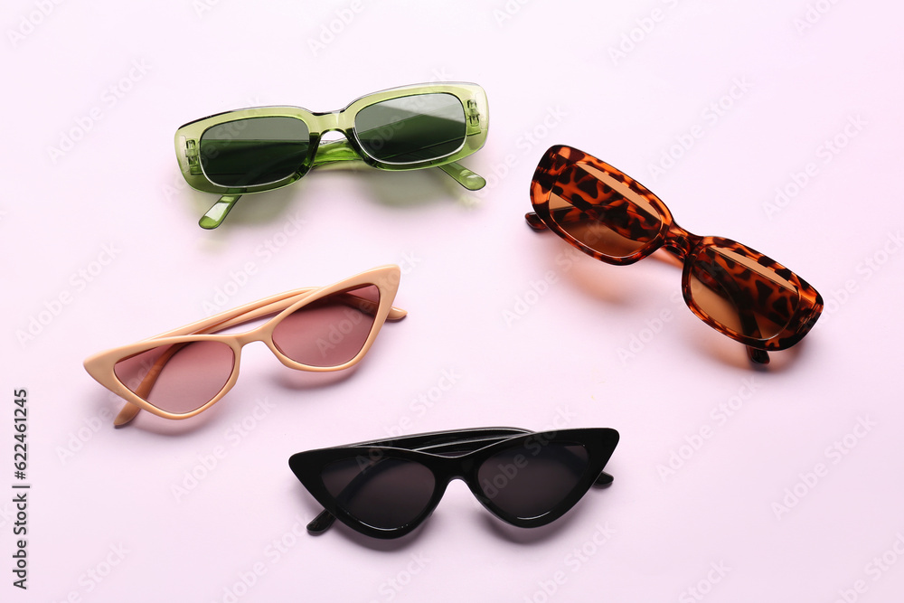 Different modern eyeglasses on pink background