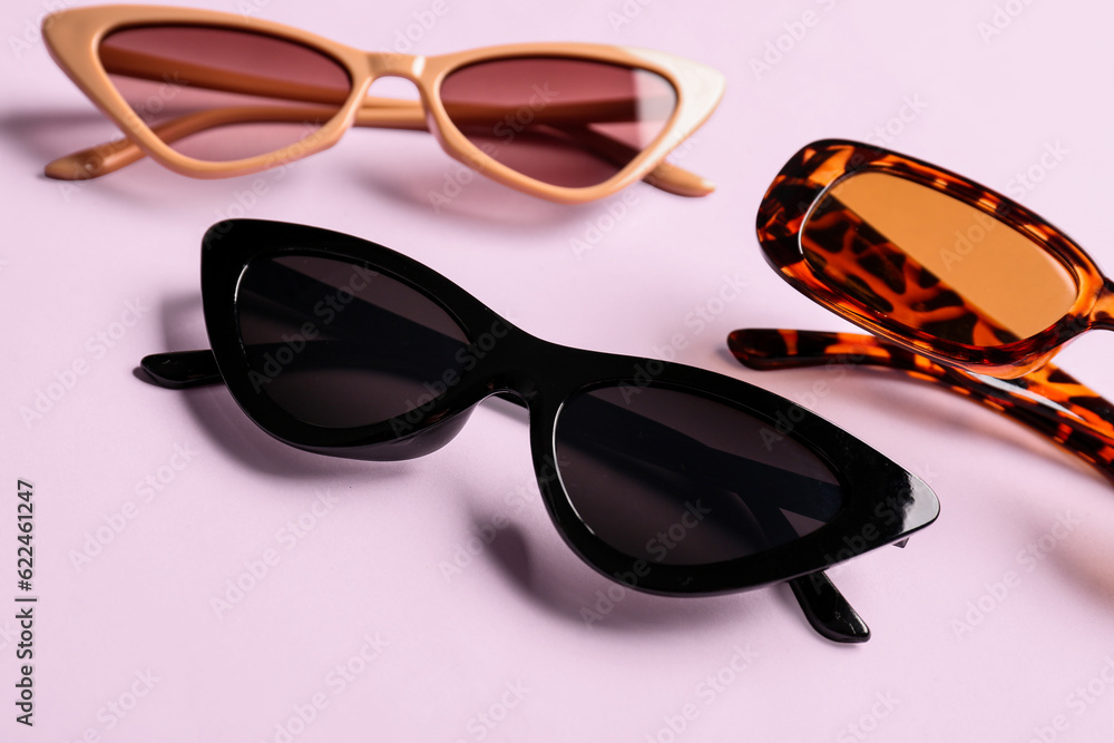 Different modern eyeglasses on pink background, closeup