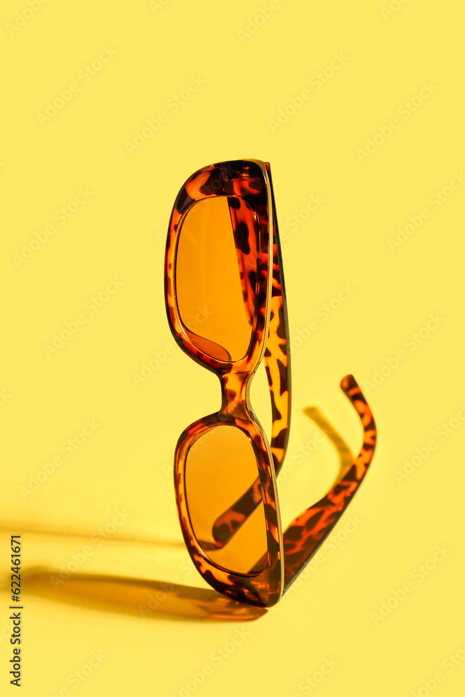 Stylish eyeglasses on yellow background