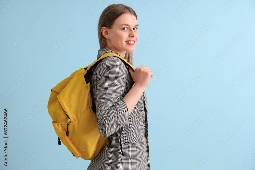 Female student with backpack on blue background