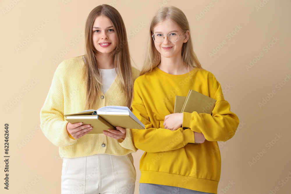 Happy female students books on pale yellow background