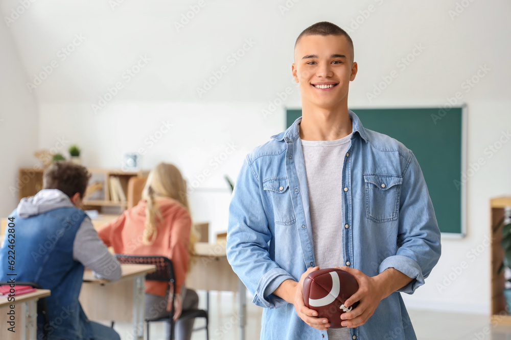 Male student with rugby ball in classroom