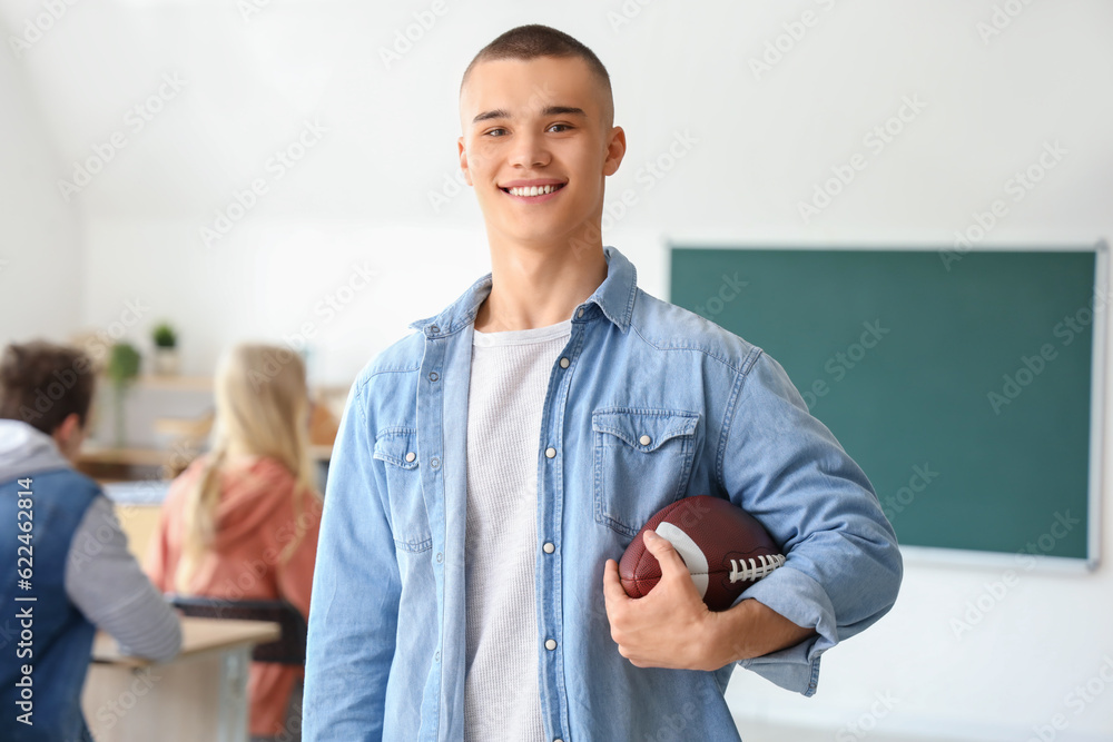 Male student with rugby ball in classroom