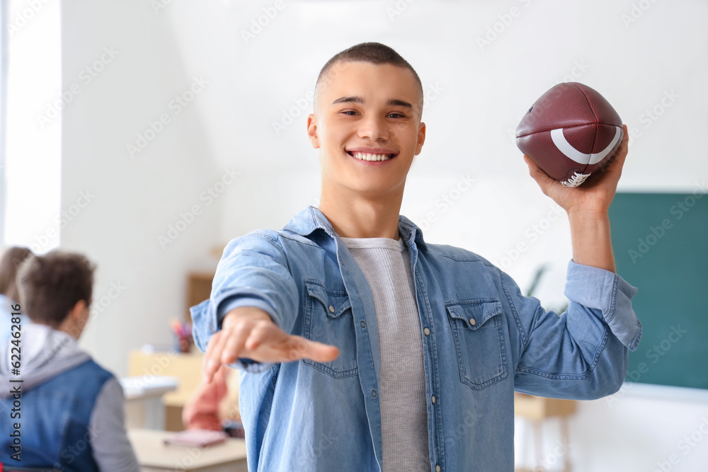 Male student with rugby ball in classroom