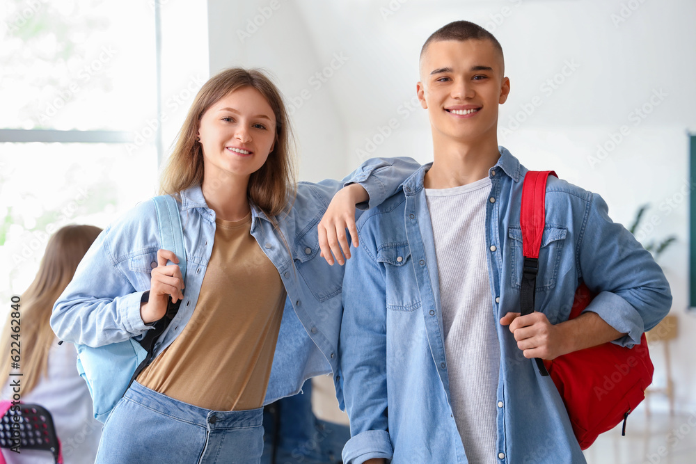 Happy students with backpacks in classroom