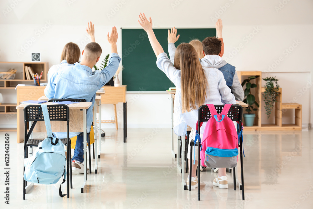 Classmates raising hands to answer in classroom