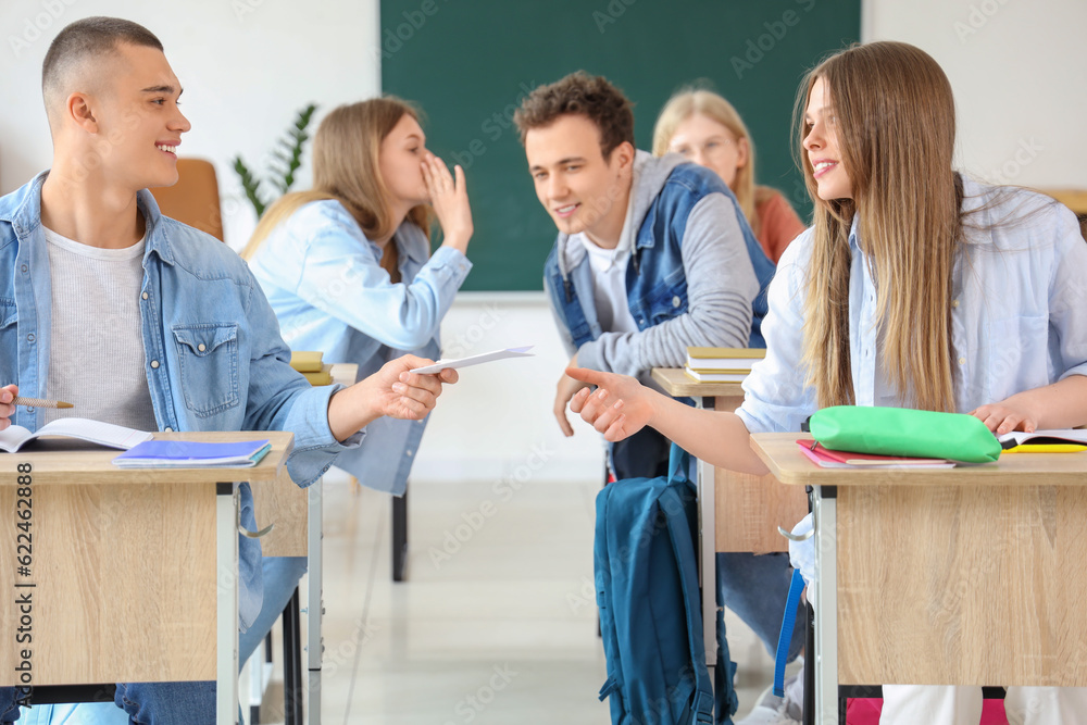 Students sitting and gossiping with his classmates in classroom