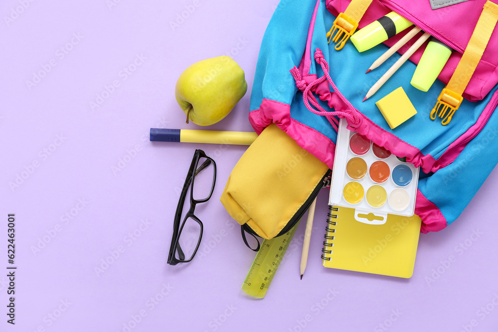 Color school backpack with pencil case, eyeglasses and apple on lilac background