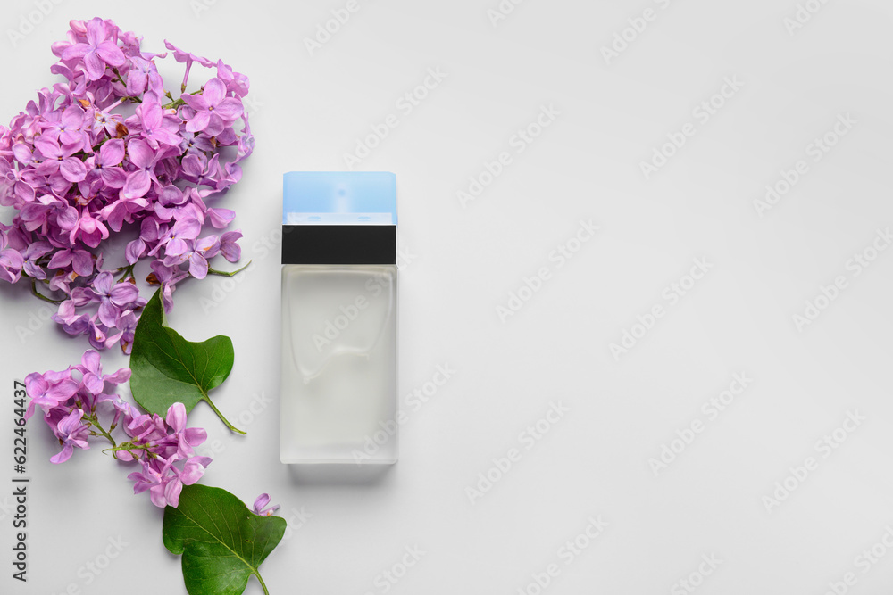 Beautiful lilac flowers and bottle of perfume on white background