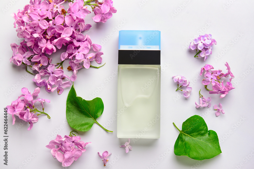 Beautiful lilac flowers and bottle of perfume on white background