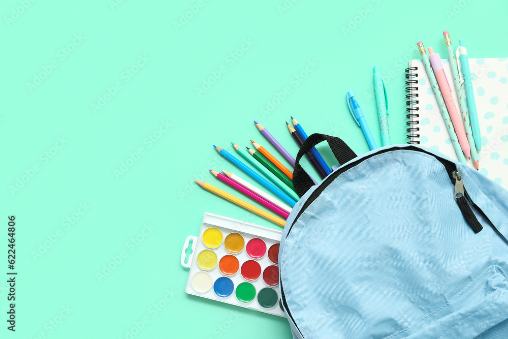 School backpack with different colorful pencils and paints on turquoise background