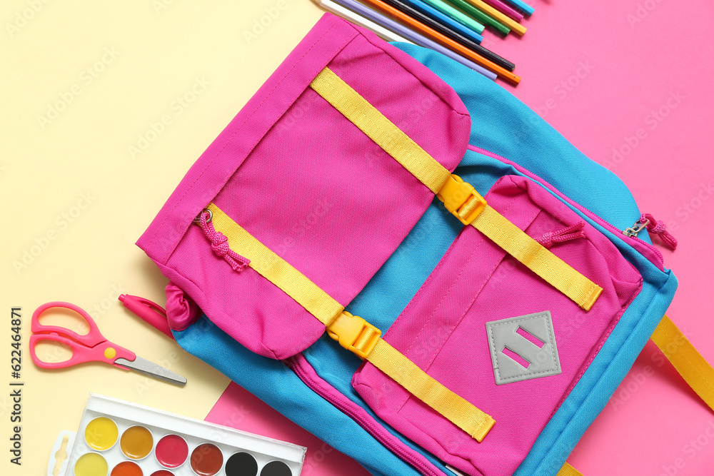 School backpack with pencils, scissors and paints on color background