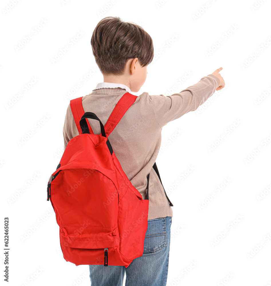 Little boy with schoolbag pointing at something on white background