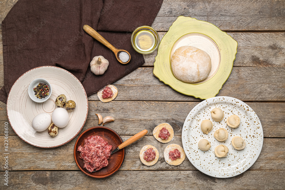 Frame made of uncooked dumplings and ingredients on wooden background