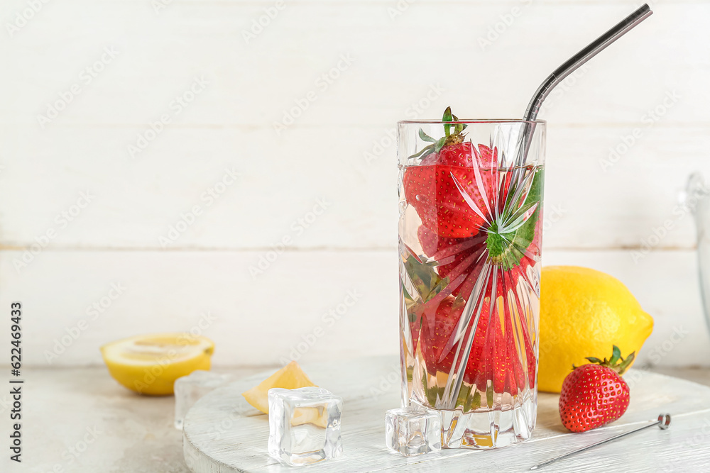 Glass of fresh lemonade with strawberry and lemon on white table