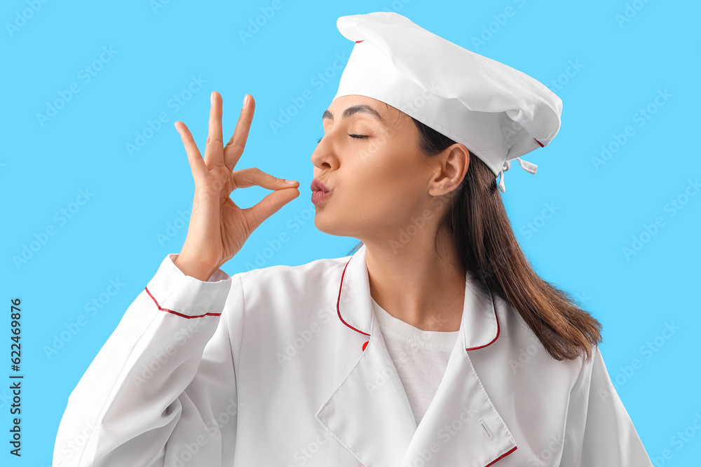 Female chef gesturing on blue background, closeup