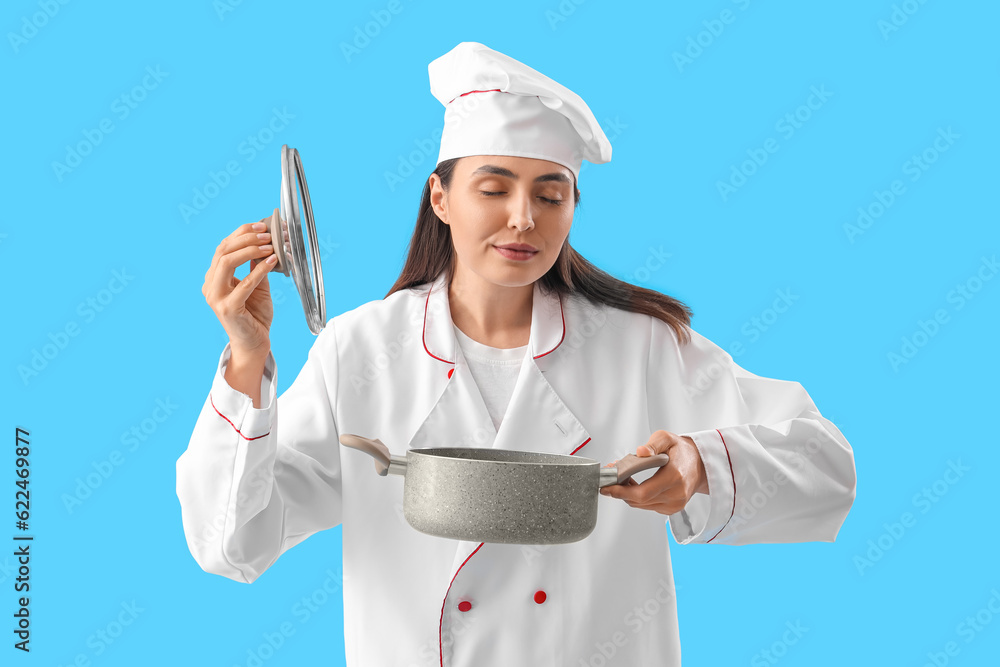 Female chef with cooking pot on blue background