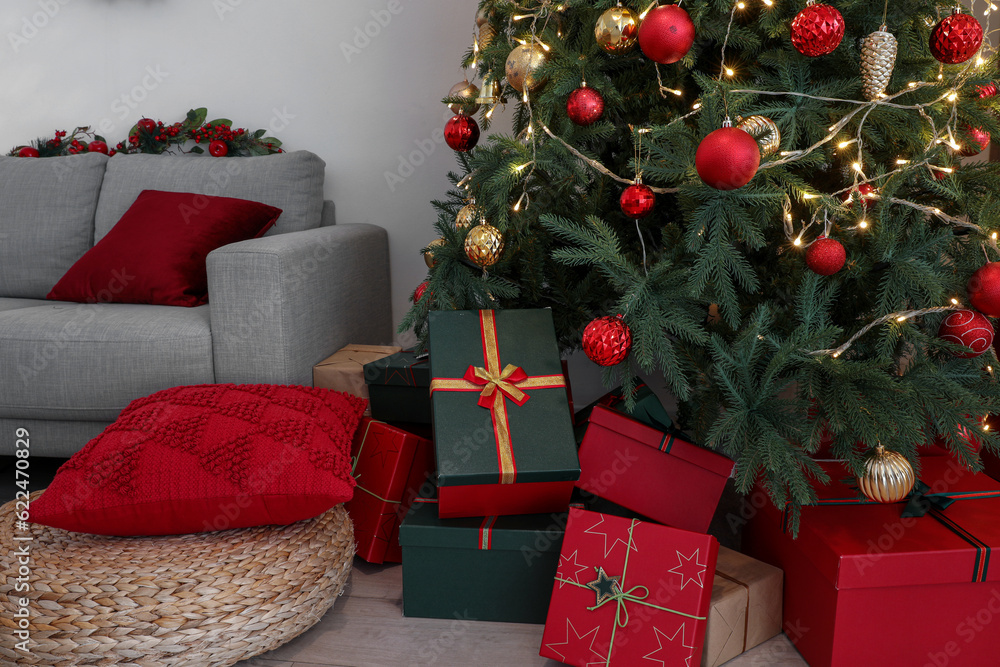 Christmas tree with glowing lights, gift boxes, red and golden balls in living room