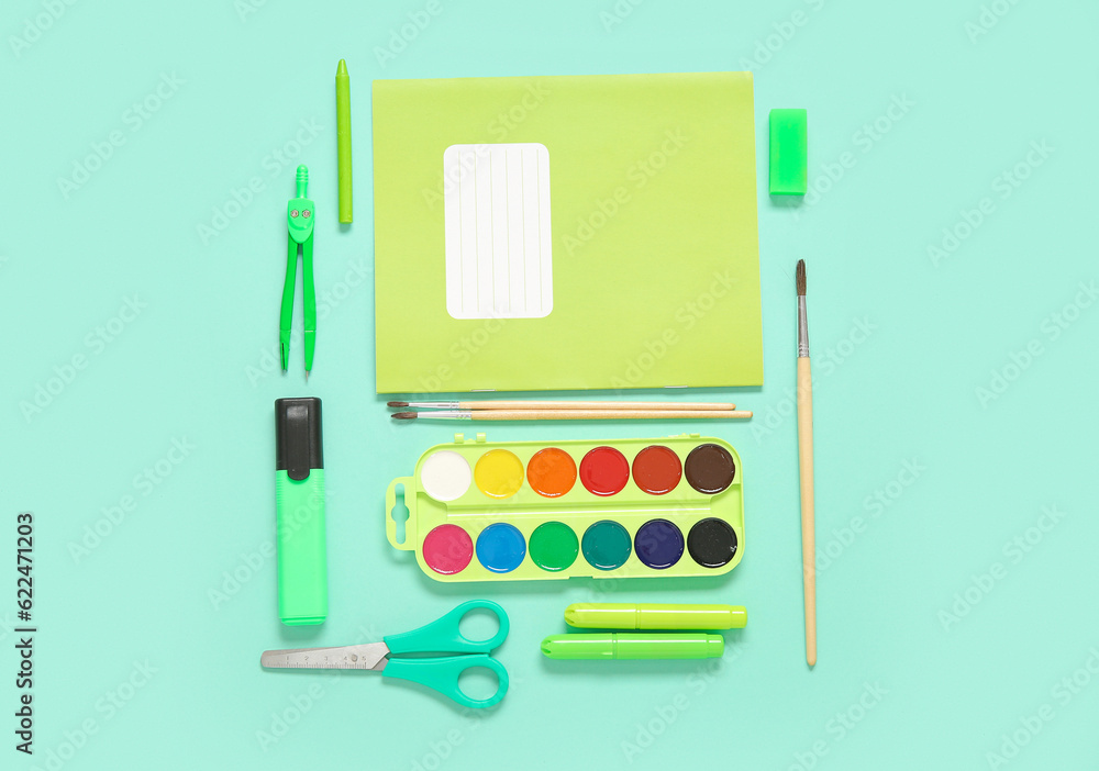 Notebook with different stationery on turquoise background