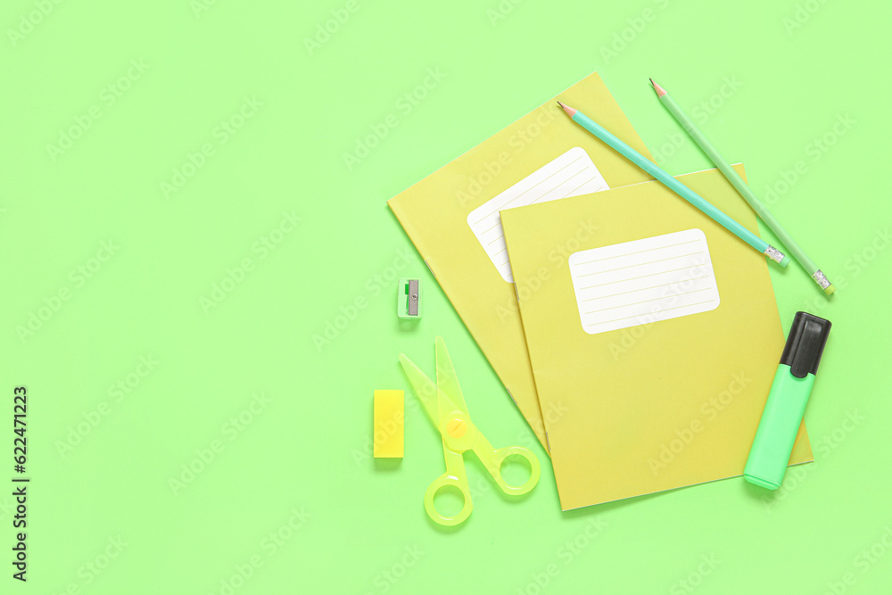 Notebooks with different stationery on green background