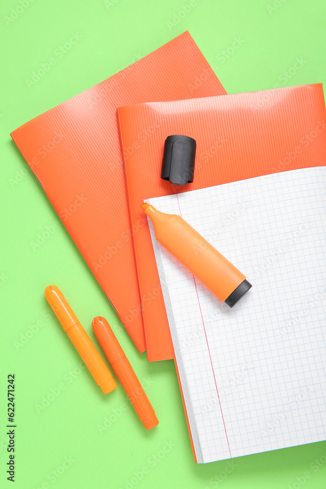 Orange notebooks with markers on green background