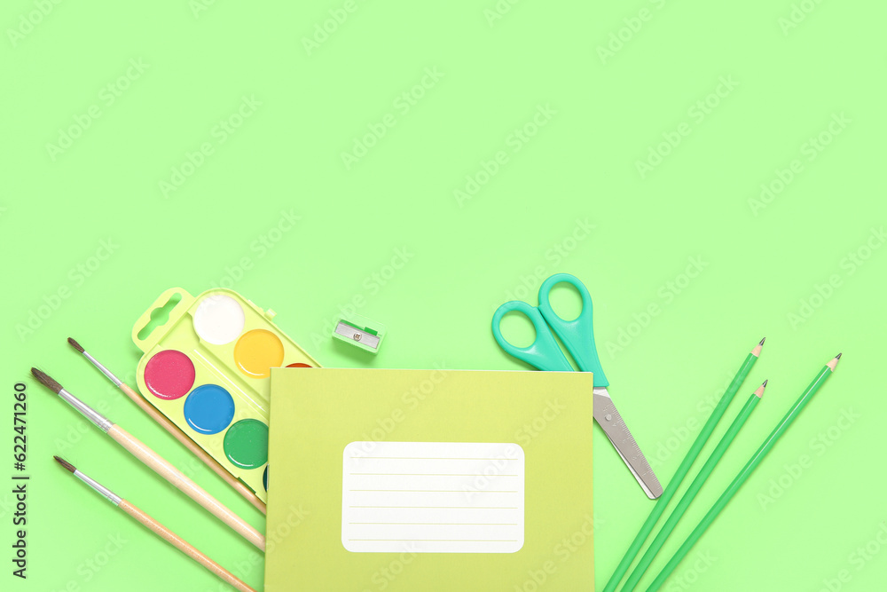 Notebook with different stationery on green background