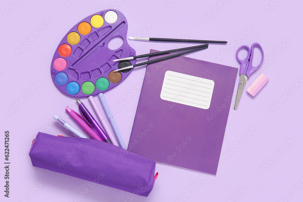 Notebook with pencil case and different stationery on purple background