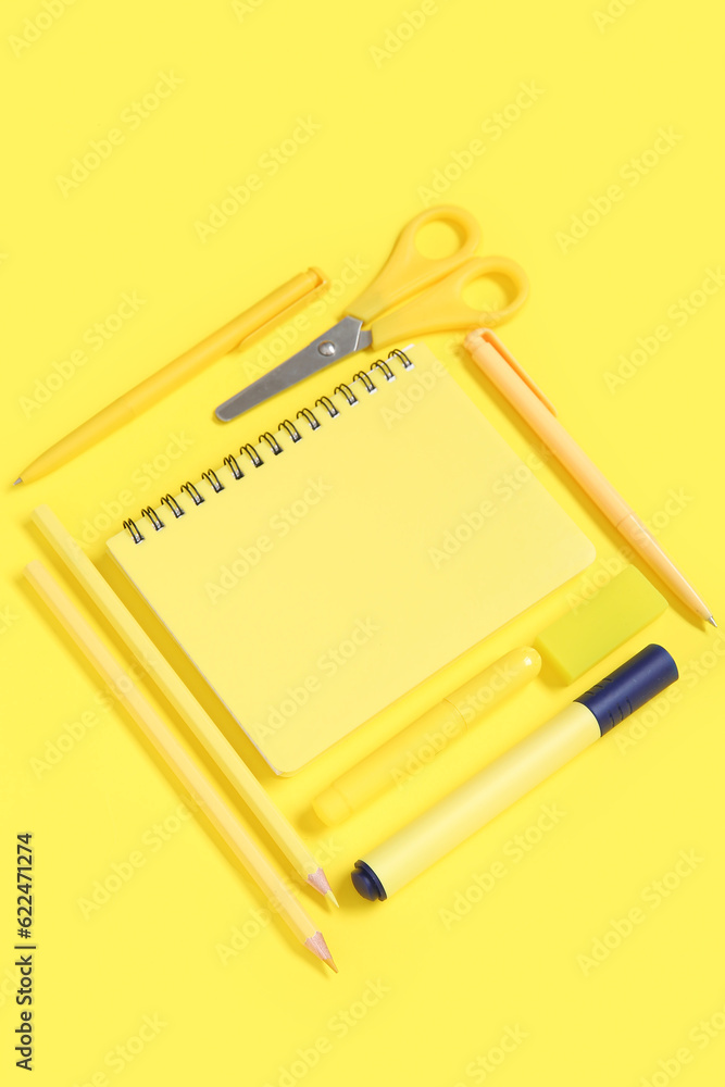 Notebook with different stationery on yellow background