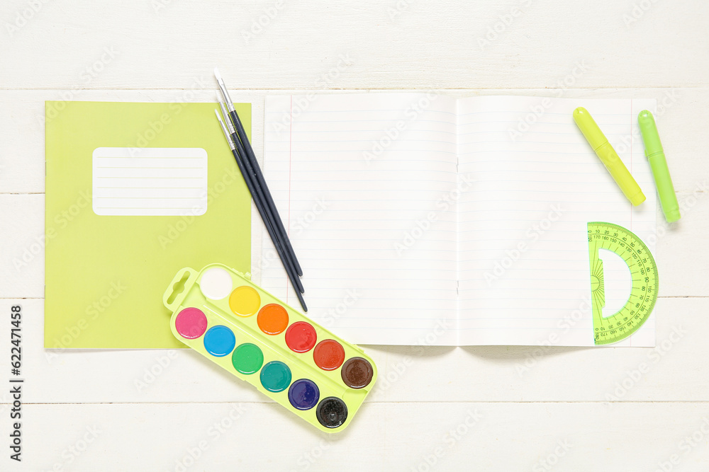 Notebooks with different stationery on white wooden background