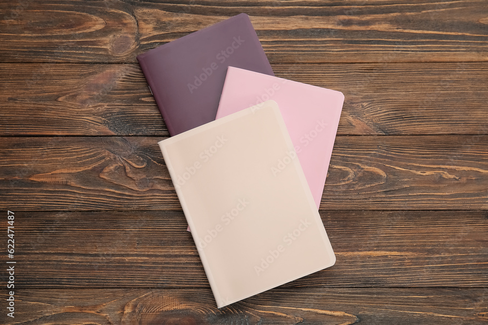 Different colorful notebooks on brown wooden background