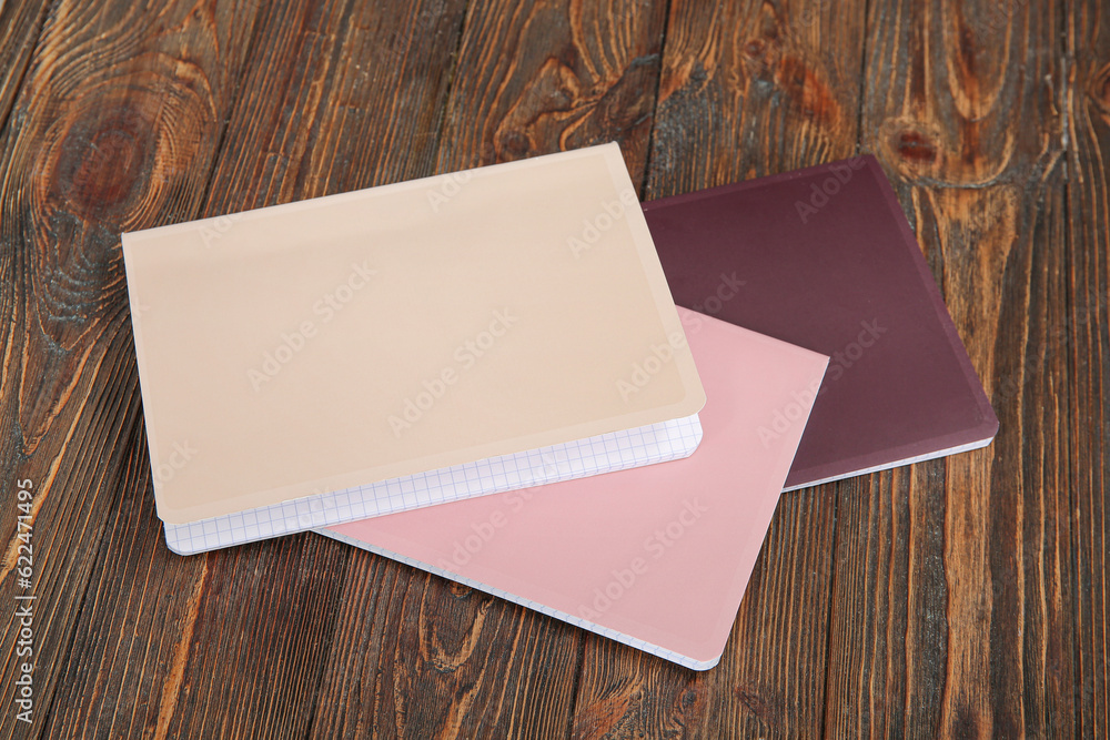 Different colorful notebooks on brown wooden background