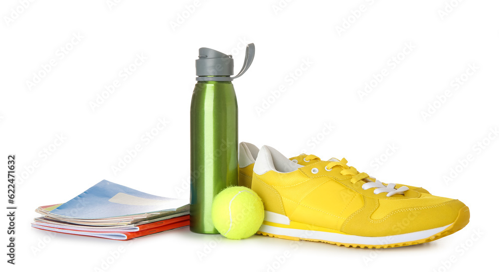 Sneakers with bottle of water, tennis ball and notebooks isolated on white background