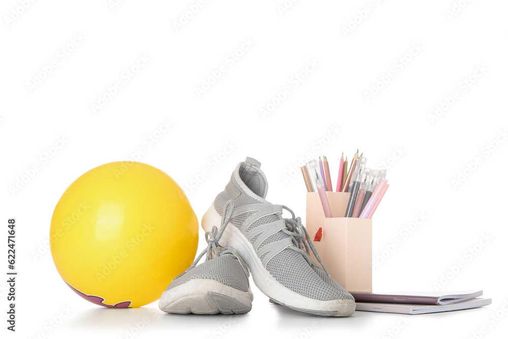 Sneakers with ball, notebooks and stationery holder isolated on white background