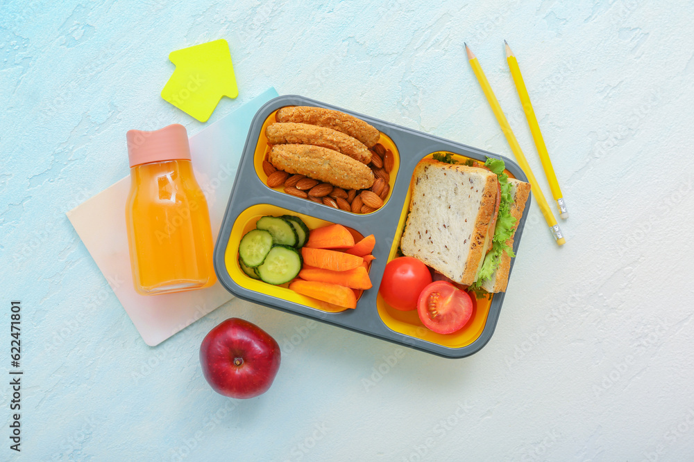 Stationery, drink and lunch box with tasty food on gradient background