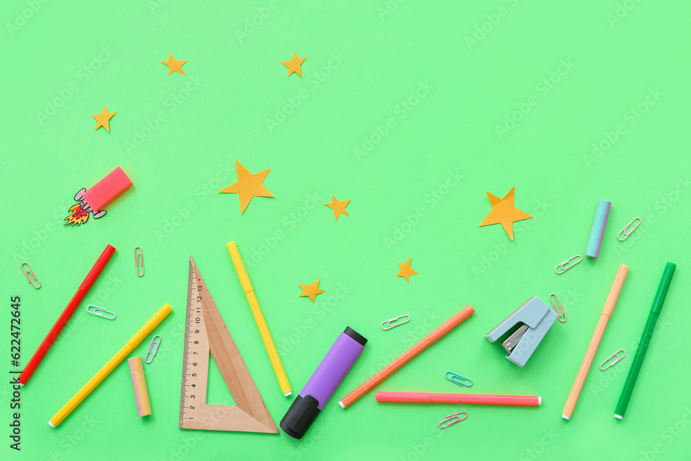 Creative composition with paper rocket, stars and different stationery on green background