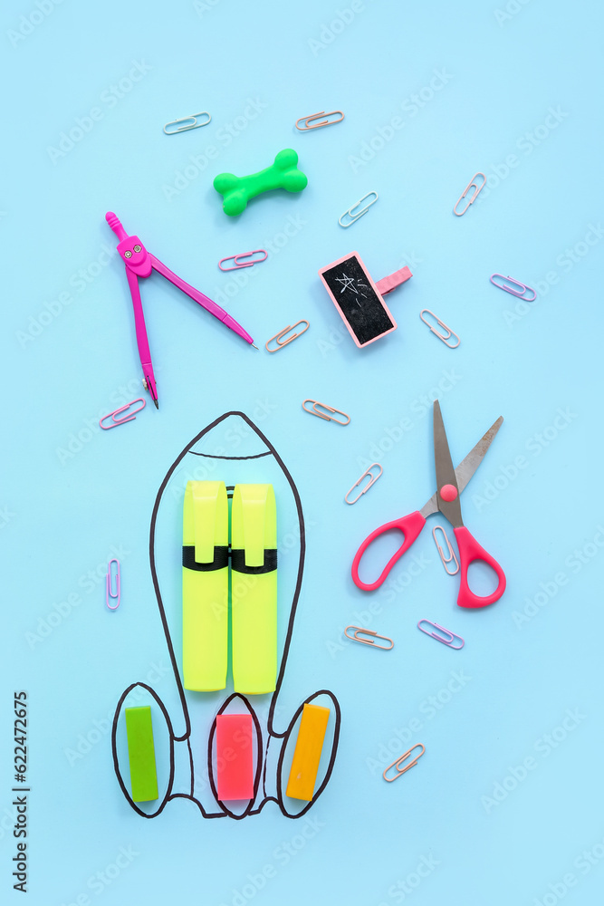 Creative composition with drawn rocket and different stationery on blue background