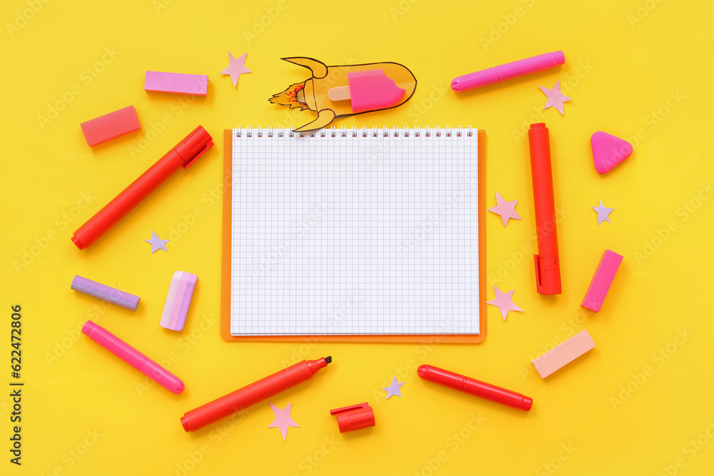 Creative composition with blank notebook, paper rocket and different stationery on yellow background