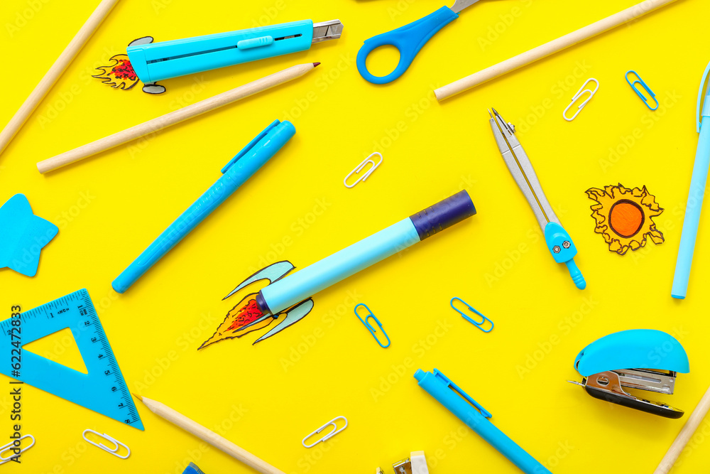 Creative composition with paper rockets and different stationery on yellow background