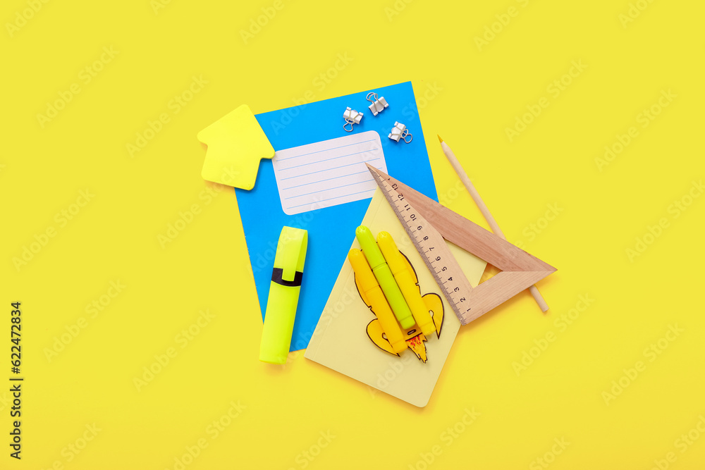 Creative composition with paper rocket and different stationery on yellow background