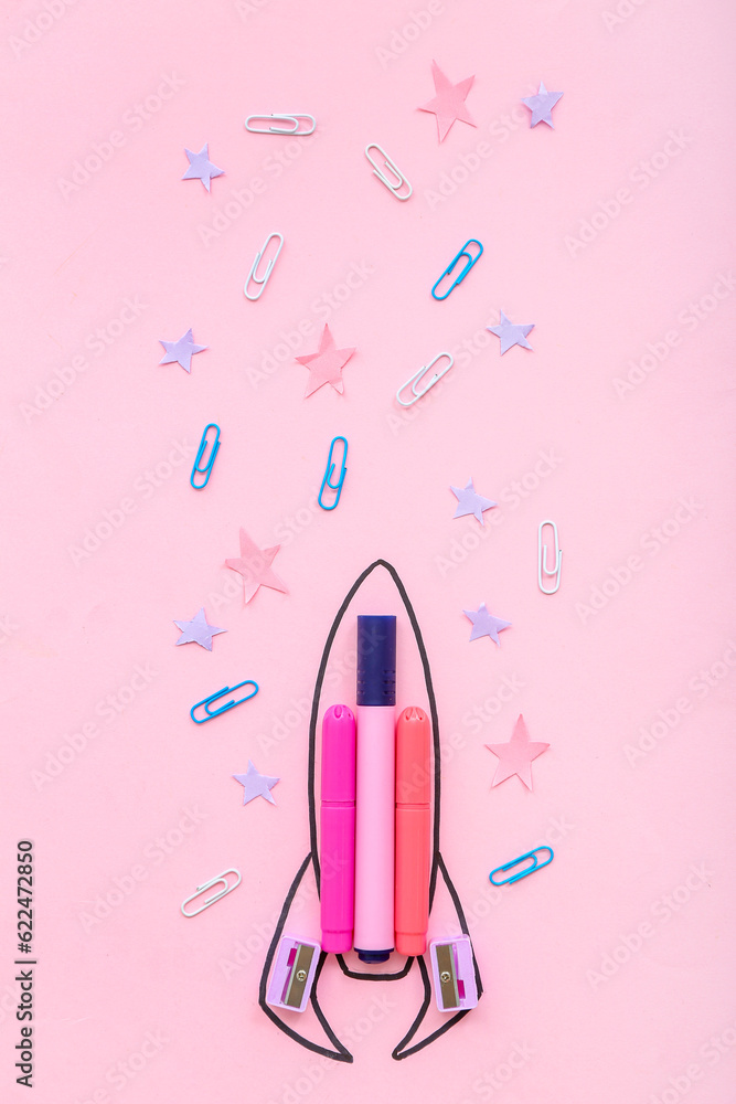 Creative composition with drawn rocket and different stationery on pink background