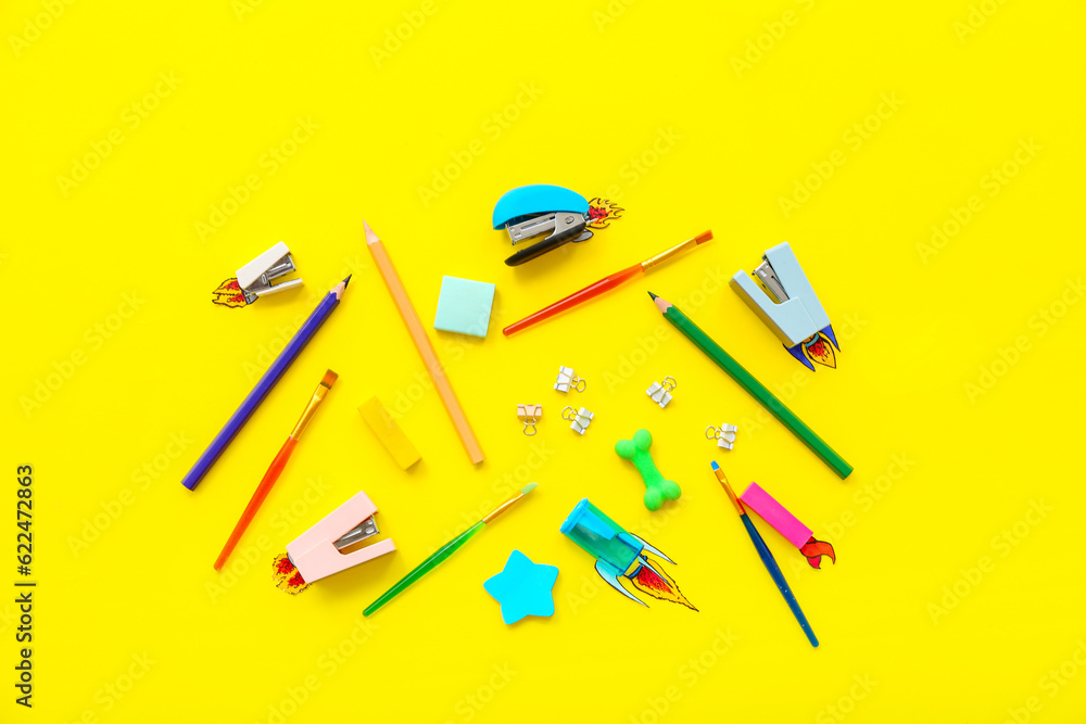 Creative composition with paper rockets and different stationery on yellow background