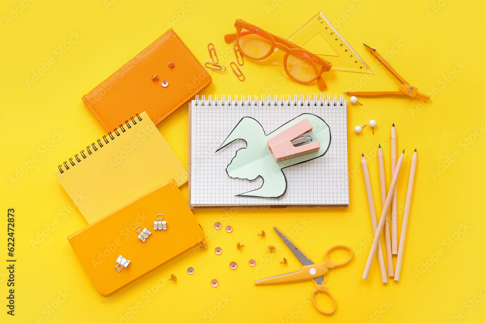 Creative composition with paper rocket and different stationery on yellow background