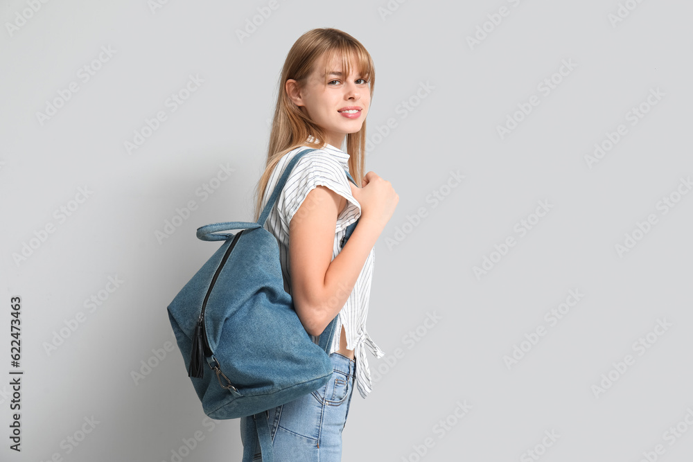 Female student with backpack on light background