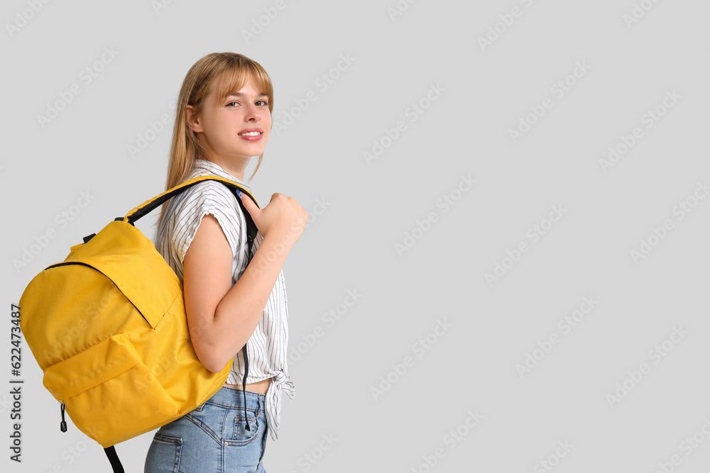 Female student with backpack on light background